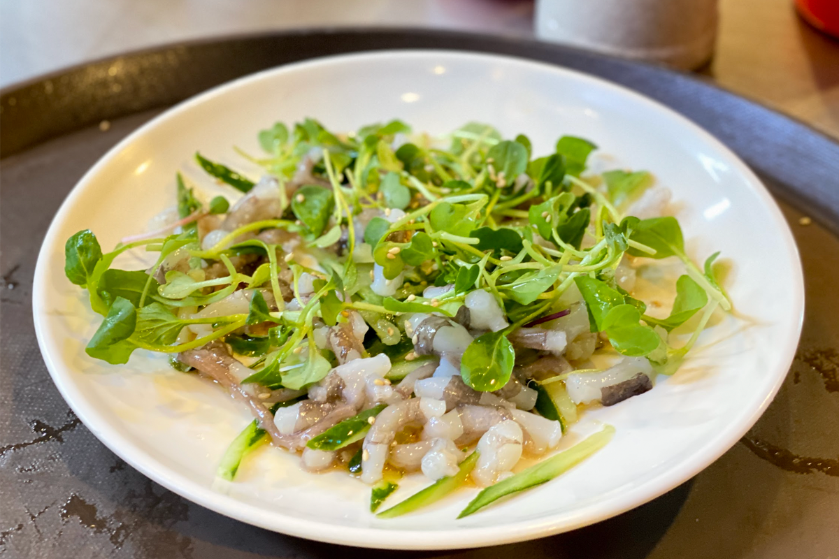 一道盛滿著生章魚的菜餚，佐以綠色植物，展現出韓國料理中海鮮的精緻與新鮮。