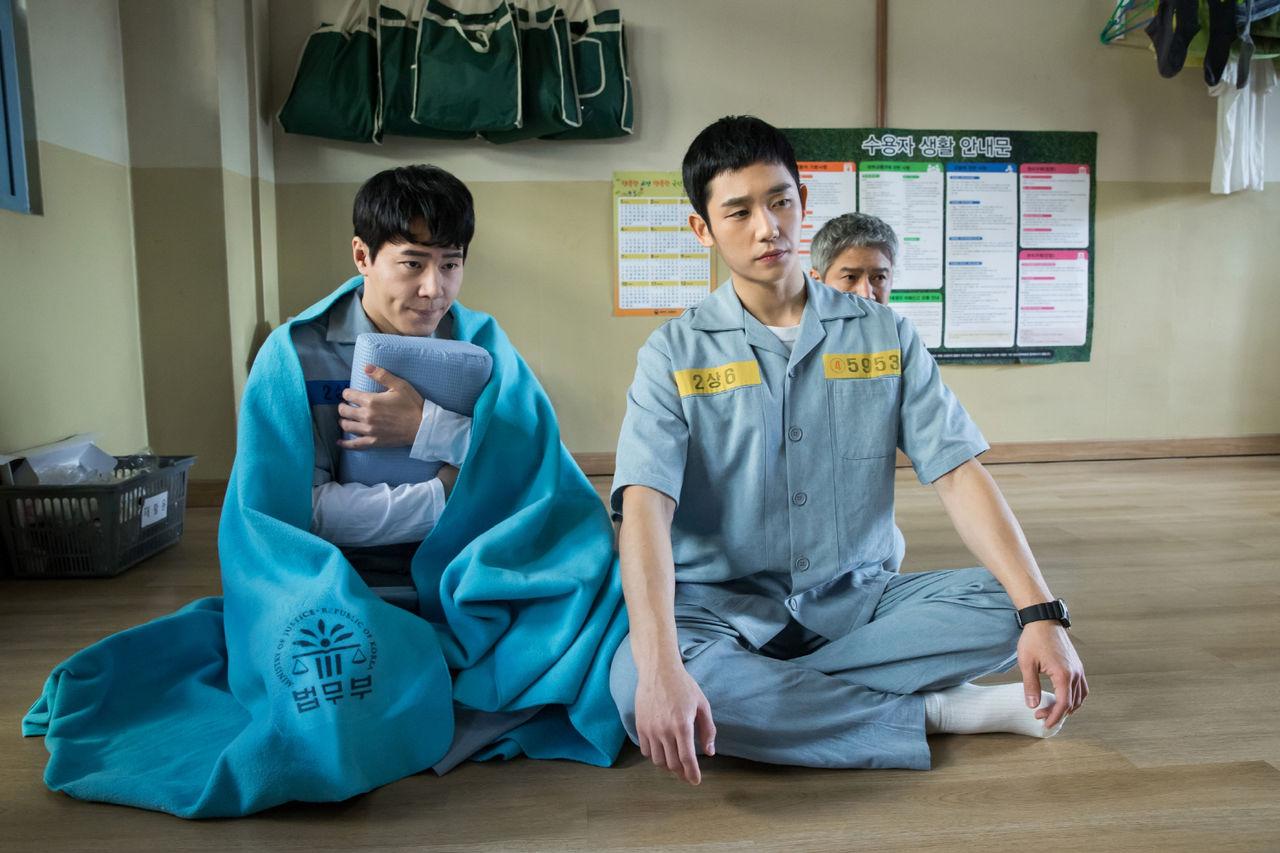 刑務所のルールブック、囚人のユニフォームを着た人物がフロアに座っているシーン