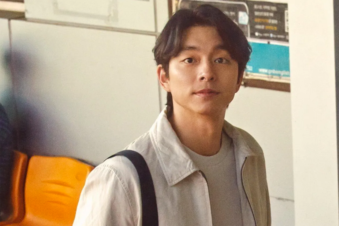 孔劉站在戶外的照片，身穿休閒服，背景模糊的風景。