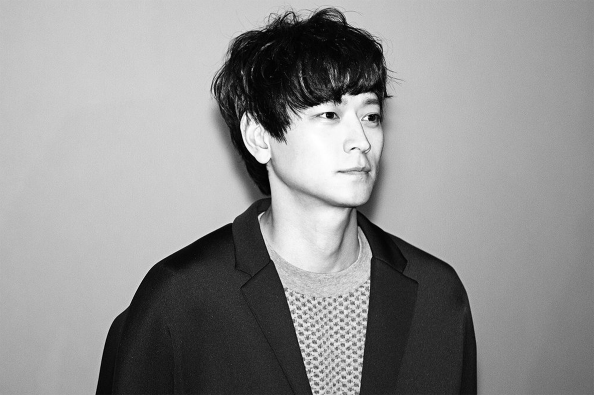 姜棟元的黑白室內側身照片，身穿休閒外套。