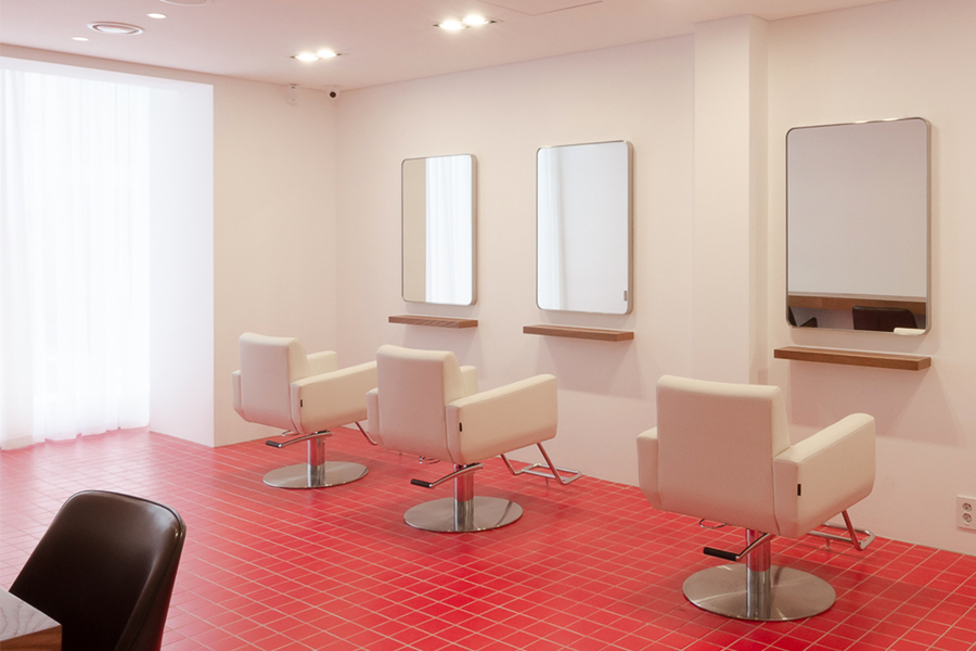 AM:TON 髮廊的美髮區，紅色瓷磚地板和白色牆壁搭配，現代感十足的剪髮座椅。
