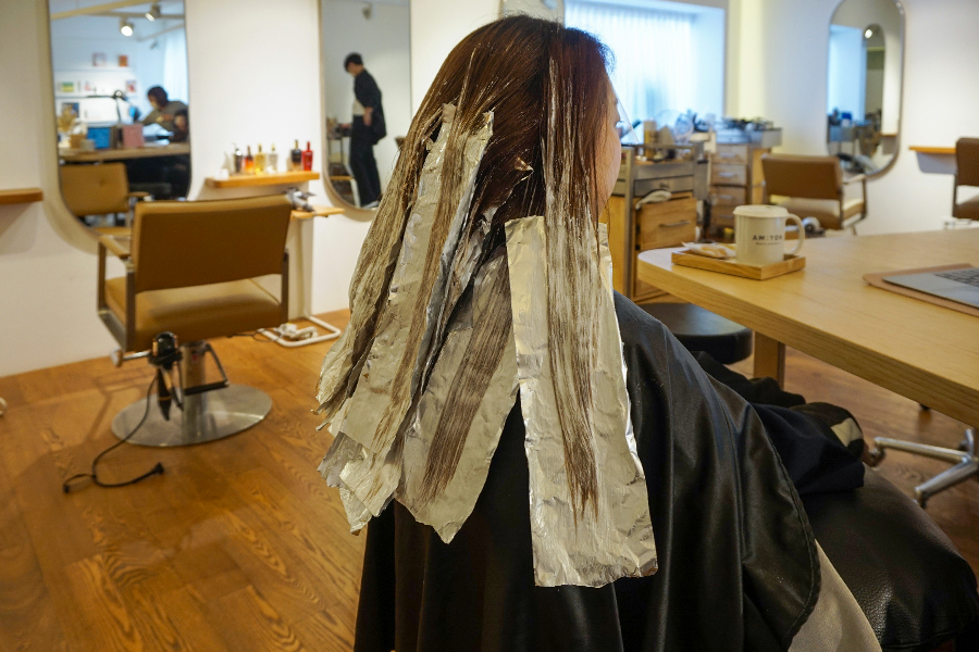 被吹乾髮絲的顧客在 AM:TON 髮廊，髮型師專業技術保證髮型效果。