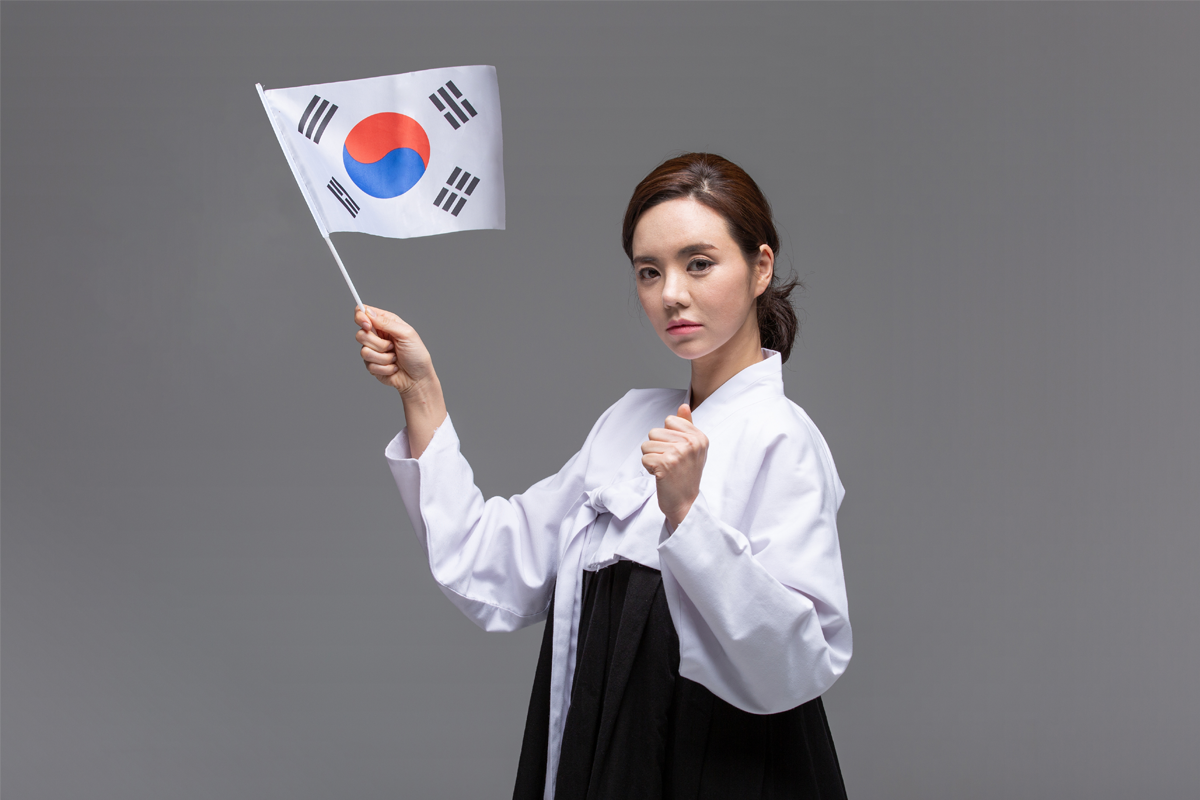 女人身穿传统韩服举着韩国国旗