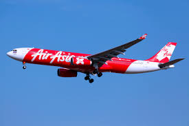 一架紅色的 AirAsia 機艙在天空中飛行,背景是藍色的天空,提供馬來西亞的無限飛行服務。「AirAsia X」是提供多個國際航班的經濟選擇,飛行範圍包括亞洲各地。