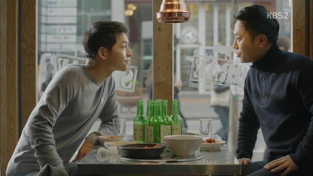 一張展示桌上擺有韓國傳統食物和多瓶韓國燒酒的照片，背景是一間韓國餐廳的室內場景。