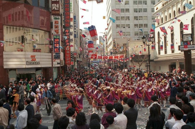 明洞街道1989年旧照片，展示热闹商圈和封街游行的画面