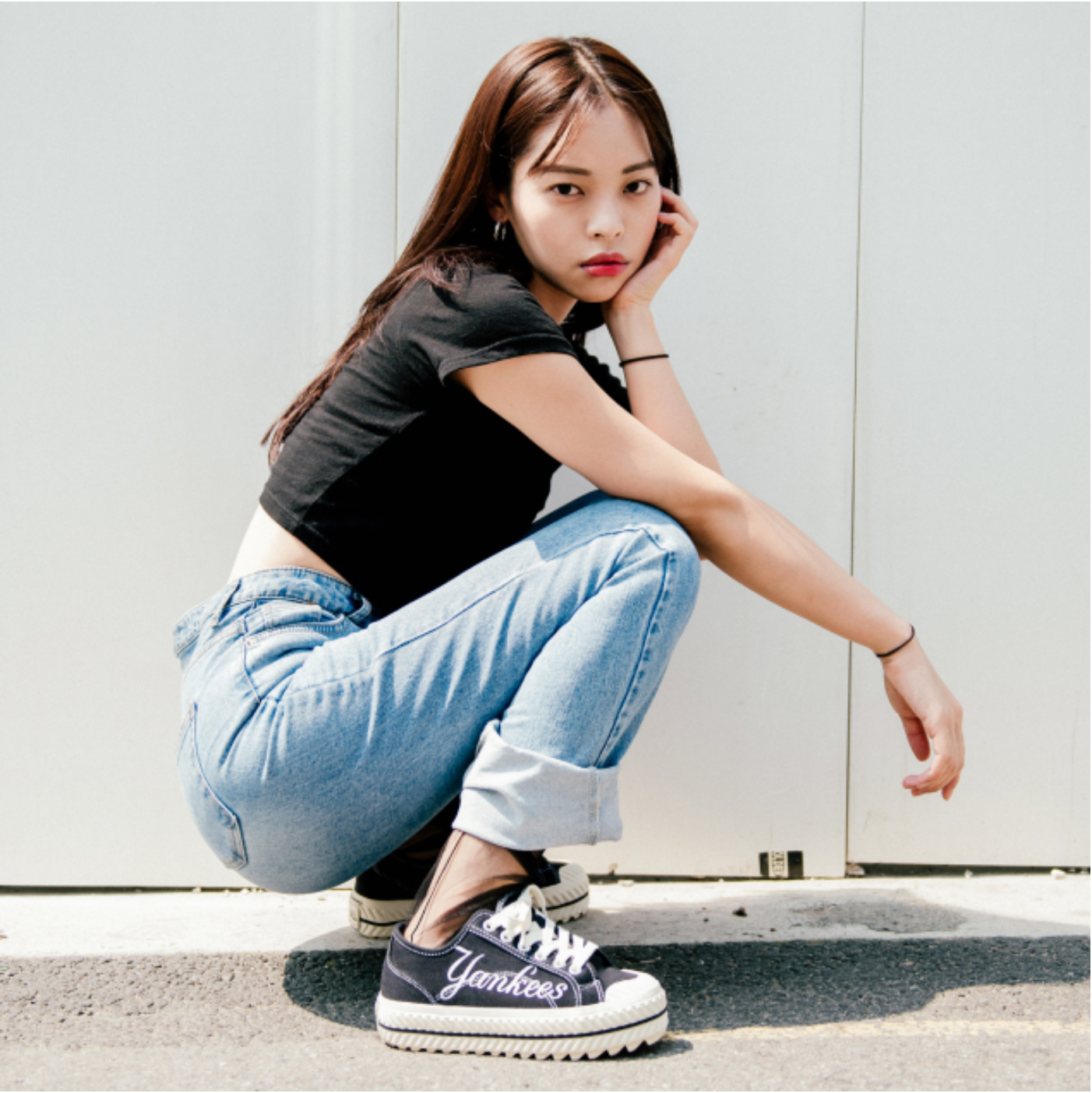 ผู้หญิงสวมรองเท้า MLB รุ่น Play Ball Chunky New York Yankees สีดำ กับกางเกงยีนส์สีฟ้า