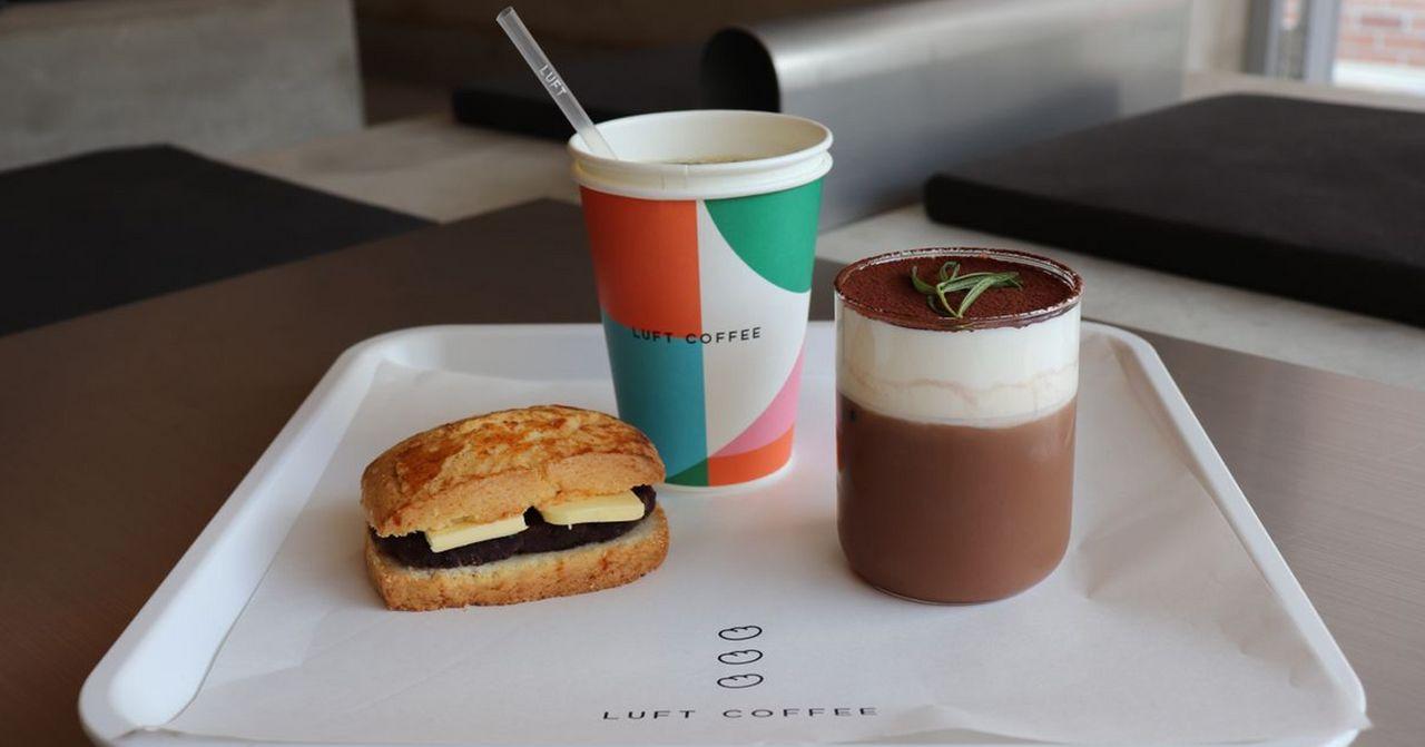 在Luft咖啡廳中擺放在託盤上的精緻韓國三明治和奶蓋咖啡，展示簡約現代的咖啡店氛圍。