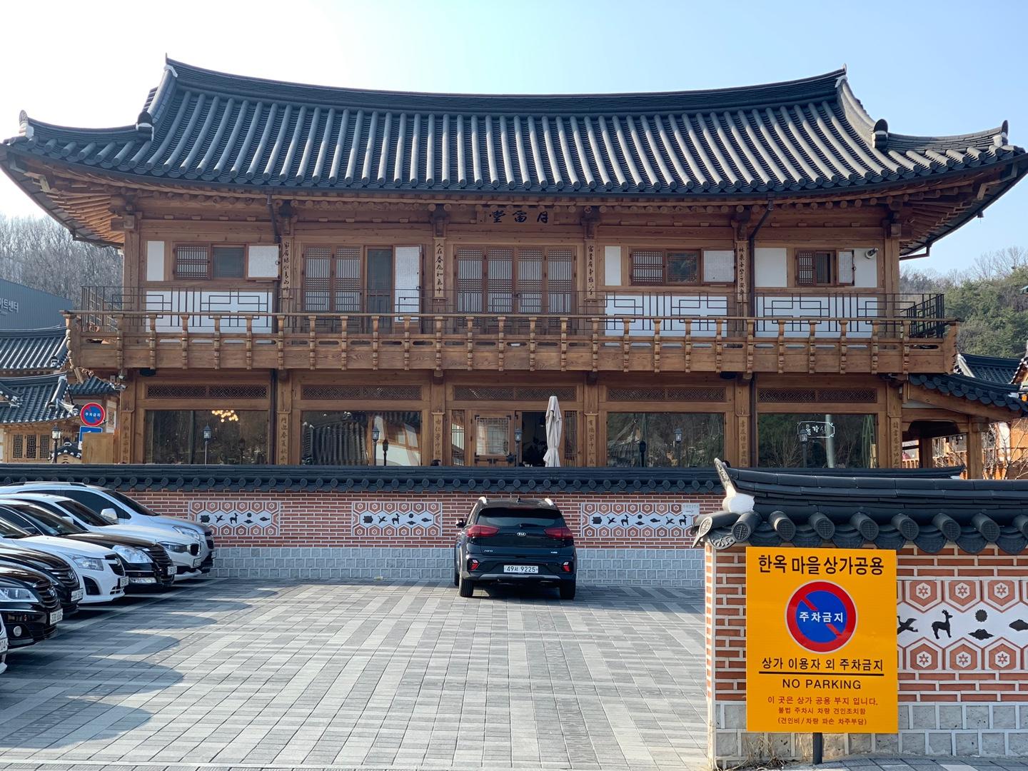 Two-story hanok building with a parking space in Eunpyeong Hanok Village, featuring traditional Korean architectural details like wooden beams and curved roof tiles.