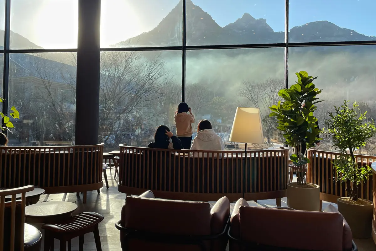 Interior of Starbucks THE Bukhansan with floor-to-ceiling windows framing the stunning view of Bukhansan Mountain in Seoul, Korea. Customers enjoy leisure time with coffee.