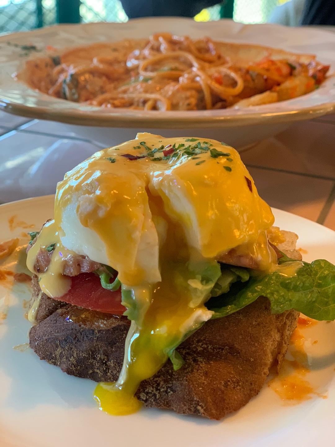 Close-up of Eggs Benedict on a slice of bread topped with a perfectly poached egg and rich hollandaise sauce.