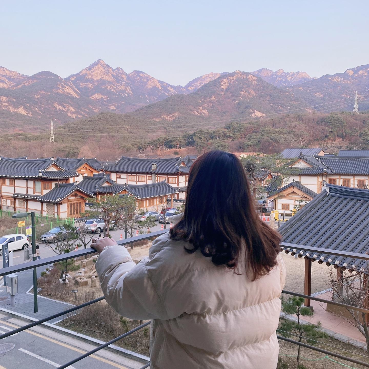 Scenic view from a vantage point in Eunpyeong Hanok Village overlooking traditional Korean rooftops and the majestic Bukhan Mountains.