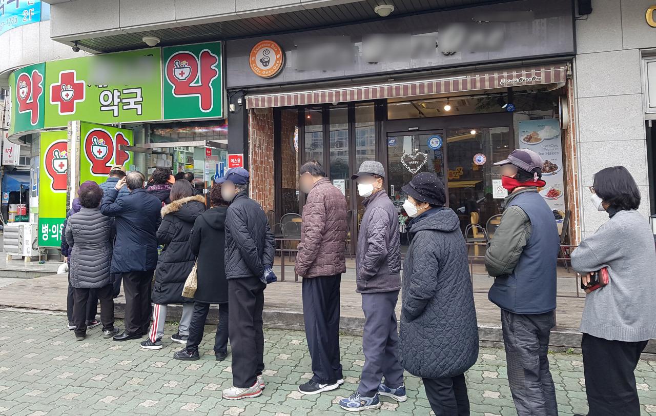 คนต่อแถวซื้อแมสก์ที่หน้าร้านขายยาในเกาหลีใต้ในช่วงการระบาดของไวรัสโคโรนา
