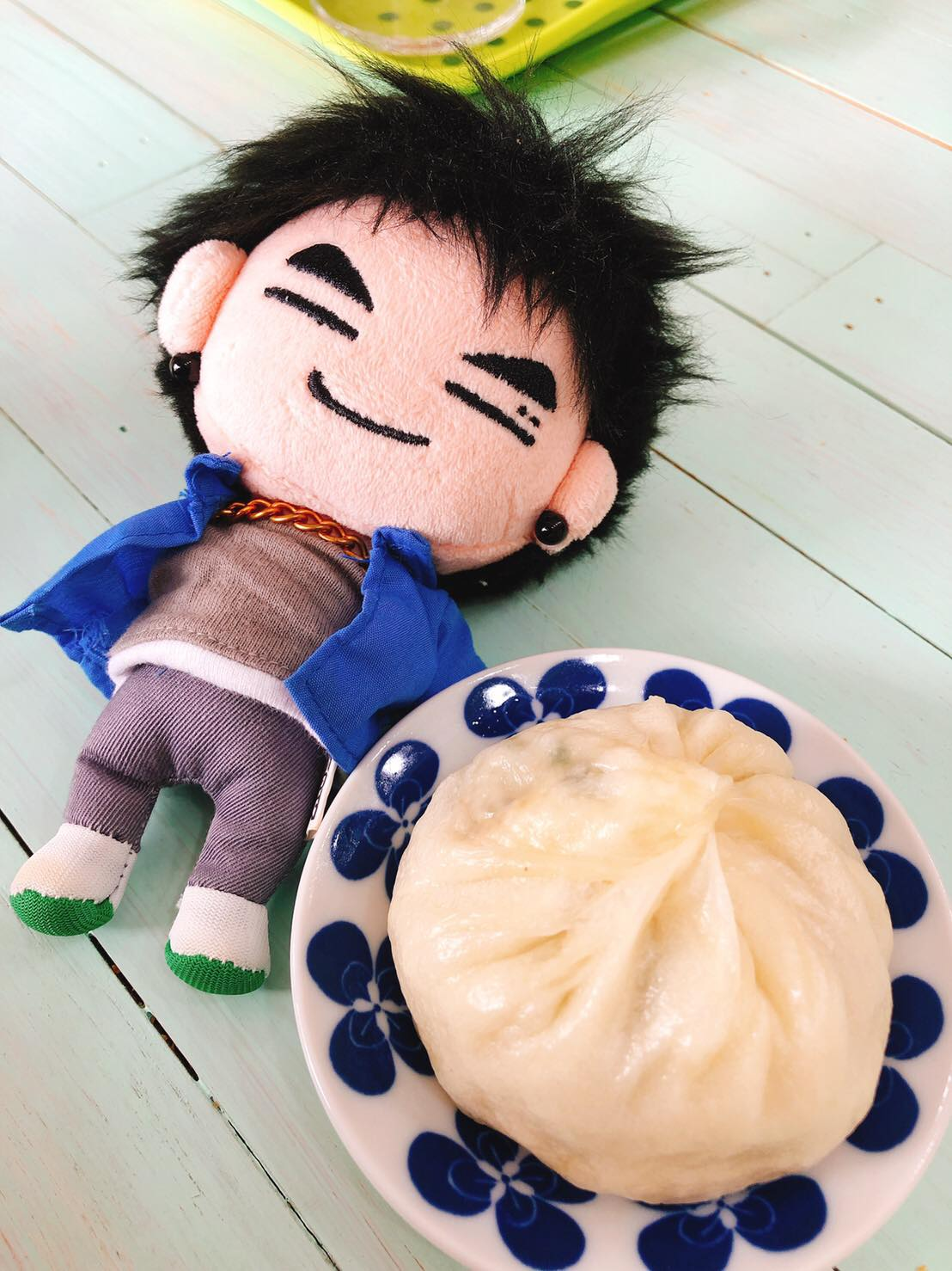 ตุ๊กตานุ่มนิ่มที่มีดีไซน์คล้ายสมาชิกวง GOT7 วางอยู่บนโต๊ะข้างพายซาลาเปาตามธีมในคาเฟ่ Yogeo Bara