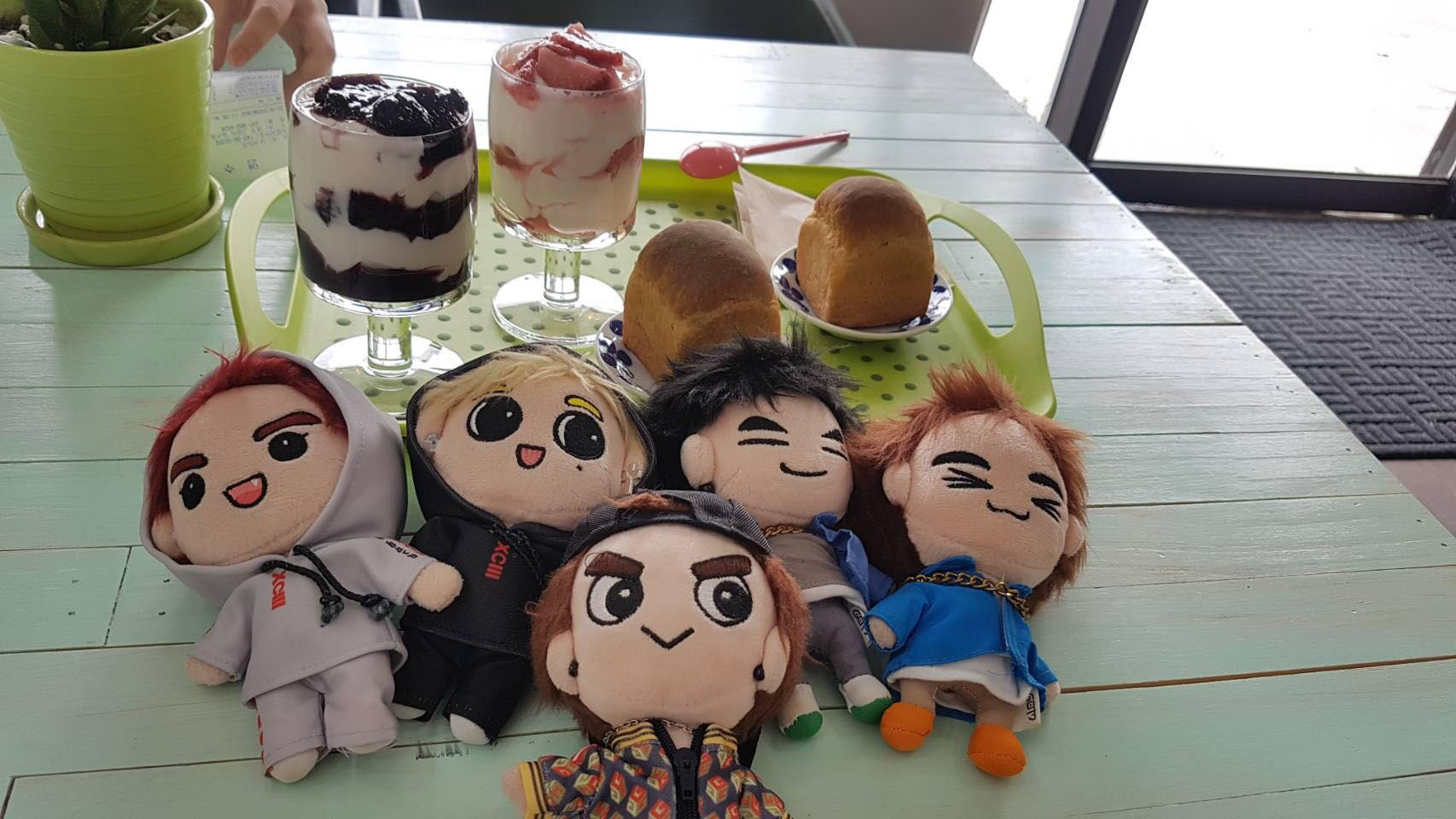 โต๊ะในคาเฟ่ Yogeo Bara ที่มีตุ๊กตาสมาชิกวง GOT7 และโยเกิร์ตเสิร์ฟพร้อมขนมปังในอิลซาน ประเทศเกาหลีใต้