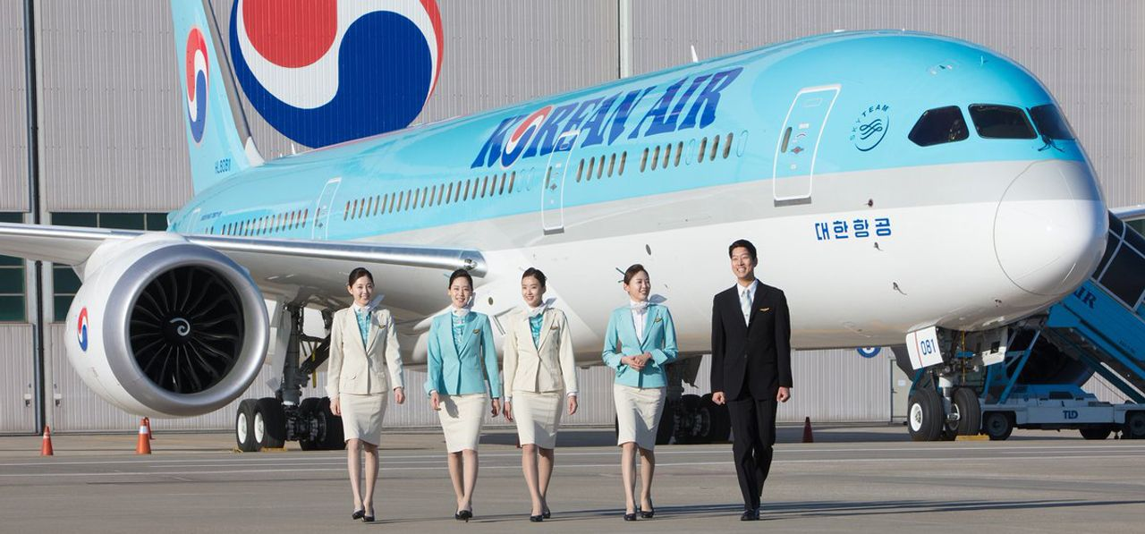 เครื่องบินของสายการบิน Korean Air และพนักงานต้อนรับบนเครื่องบินเดินบนลานจอดเครื่องบิน.
