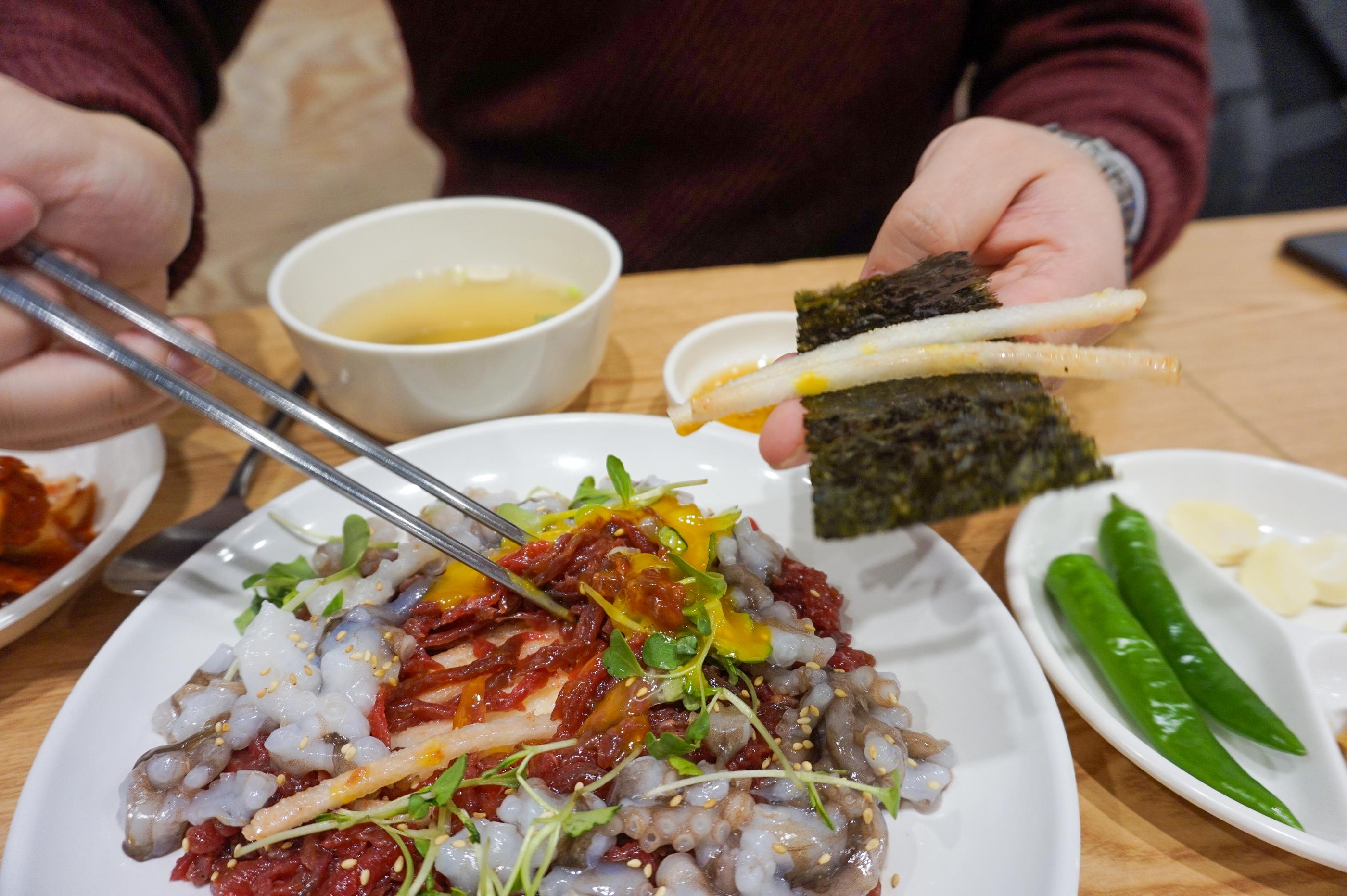 ユッケと薬味が載せられたご飯を混ぜている様子。