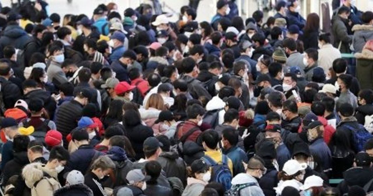 人群聚集在一起，许多人戴着口罩，显示出对公共健康的关注。