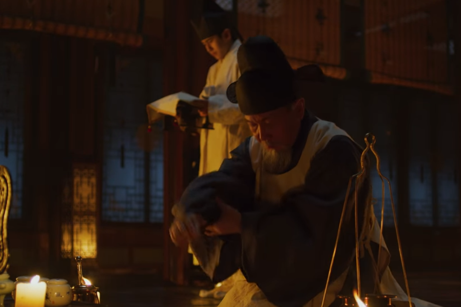 《屍戰朝鮮》中中人身穿破舊衣物站在稻草屋前。