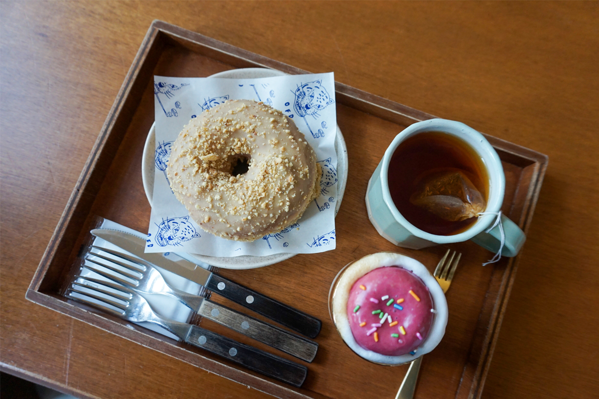 放在托盘上的花生酱甜甜圈和一杯茶,甜甜圈表面满是花生碎粒,呈现出诱人的香甜滋味。