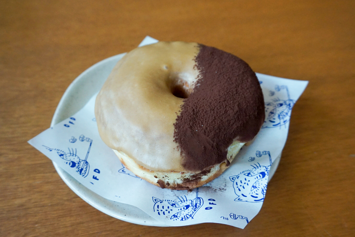 一块提拉米苏口味的甜甜圈,表面覆盖着香浓的可可粉,带来浓郁甜美的味道。