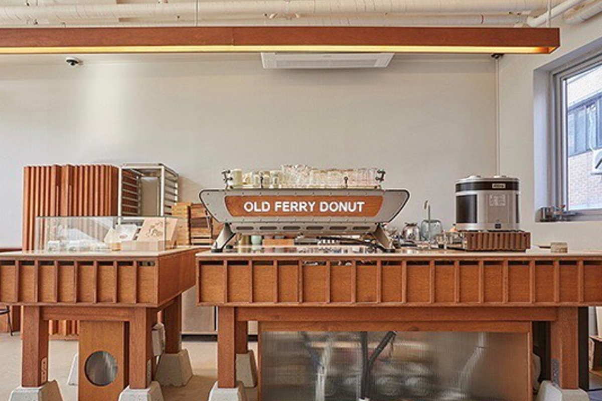 Old Ferry Donut咖啡馆内部的木质装潢,带有简约现代风格,咖啡机上方有咖啡馆的品牌标识。