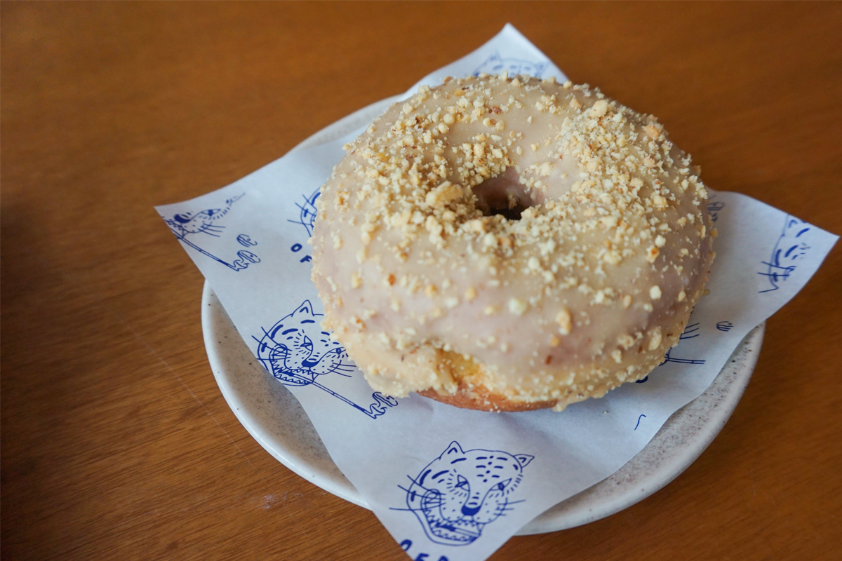 一份在盘子上的花生酱甜甜圈,表面覆上一层厚厚的花生碎粒,使其看起来更加香脆可口。