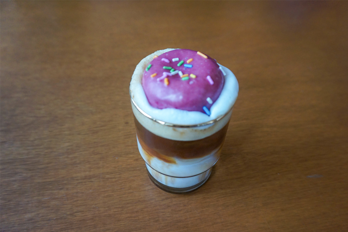 一杯咖啡上面放着一小块甜甜圈,这种独特的组合为咖啡增添了新的风味和趣味。