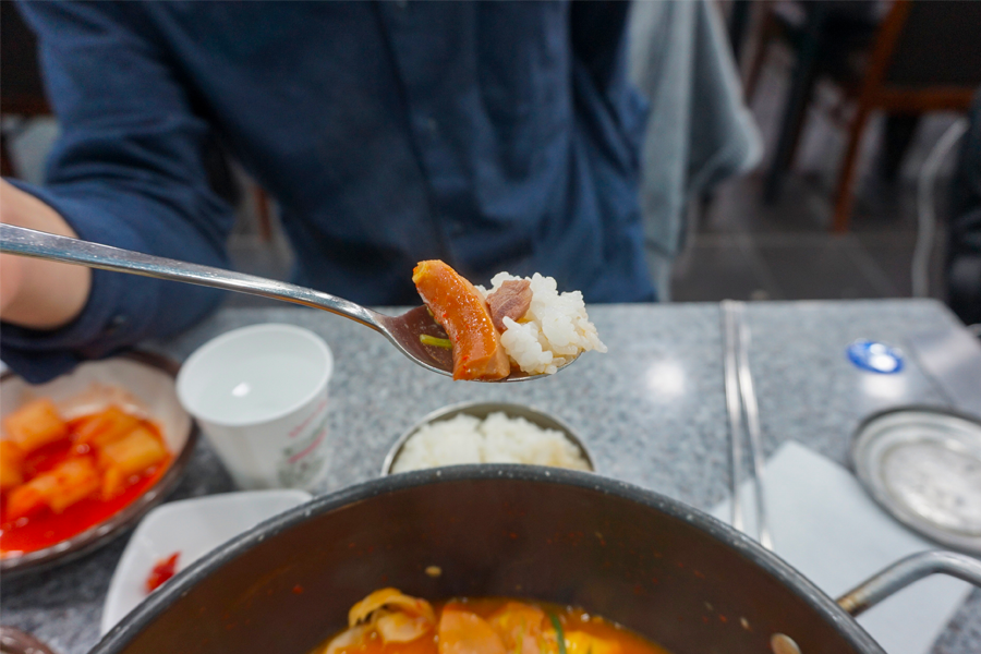 大海食堂菜肴的特写，展示了丰富的香肠和配件，搭配白饭享用。