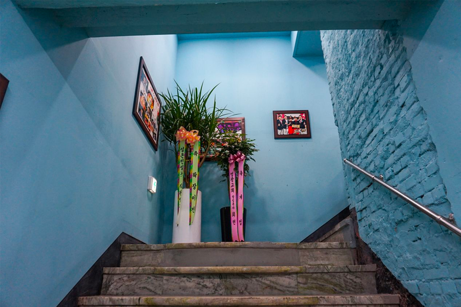 大海食堂内部的楼梯，墙上挂着植物和装饰画，通往用餐区域。