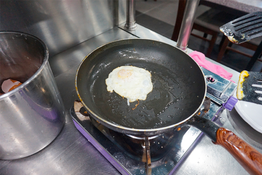 大海食堂内，顾客正在煎鸡蛋，享受DIY用餐体验。