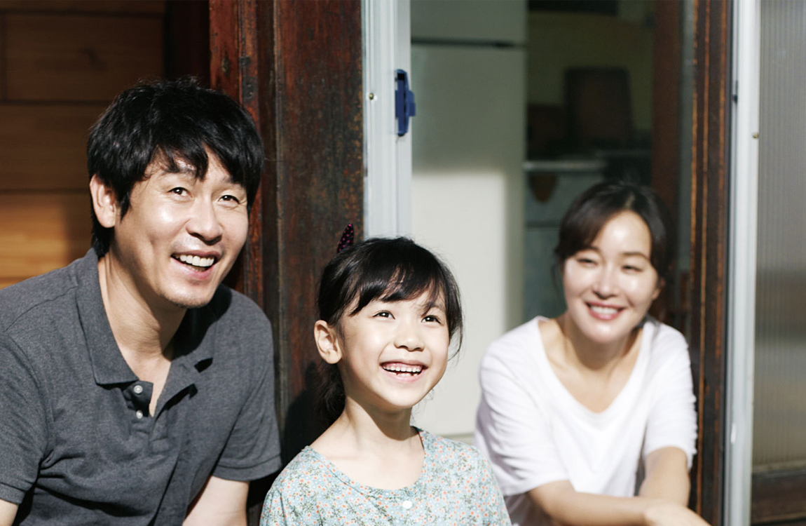 電影《希望：為愛而生》中，窗邊坐著小女孩和兩位成人，反映了電影中一個家庭的時刻。