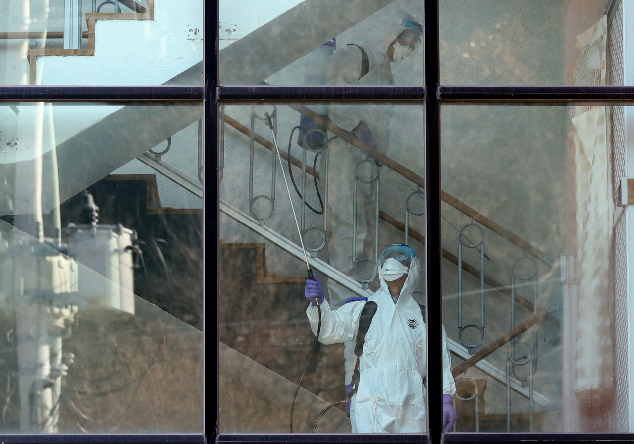 เจ้าหน้าที่ในชุดป้องกันฉีดพ่นสเปรย์ฆ่าเชื้อในสถานที่สาธารณะระหว่างการแพร่ระบาดของโควิด-19