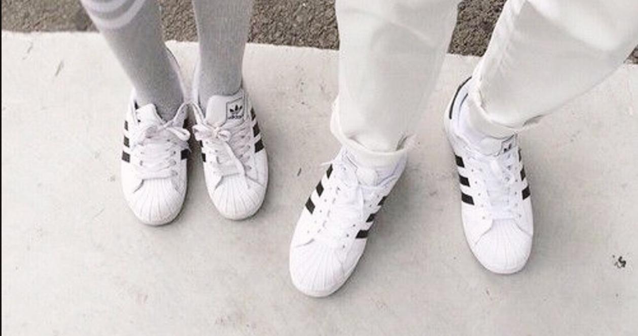 Người mang giày Adidas Superstar màu trắng, một biểu tượng thời trang không bao giờ lỗi mốt.