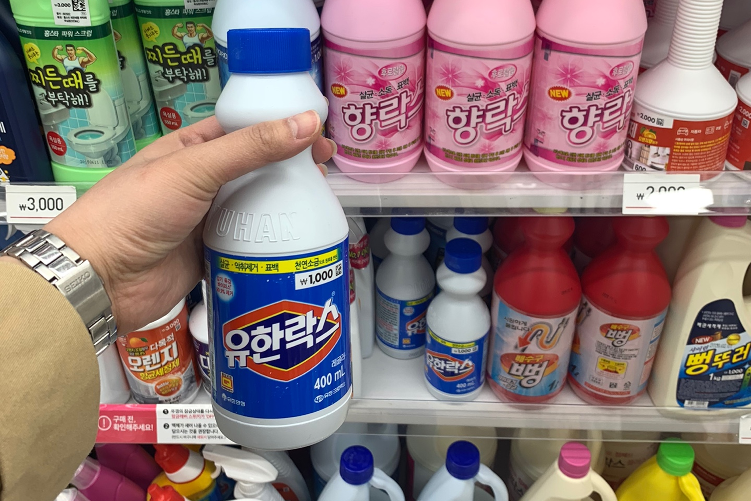 手握一瓶₩1,000的韓國Daiso漂白水，展示其在架上的位置及其他漂白水選項
