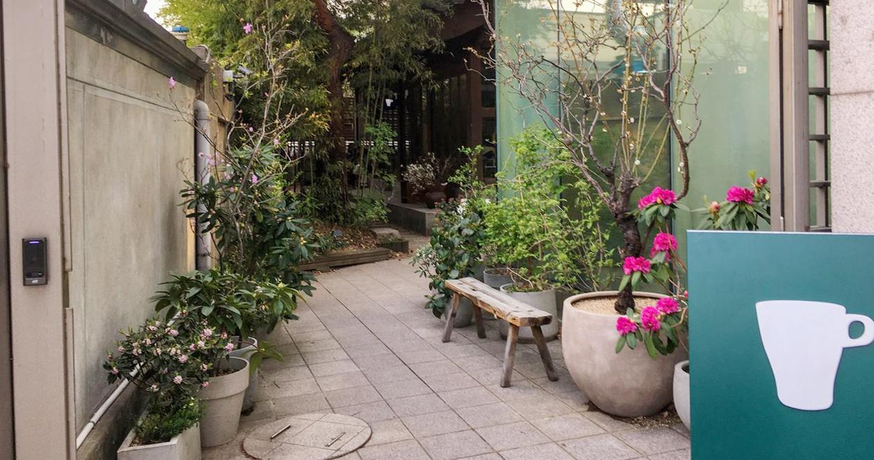 Một lối đi nhỏ xanh mát dẫn vào quán cà phê hanok xanh, điểm nhấn trong khu vực lịch sử quanh Gyeongbokgung.