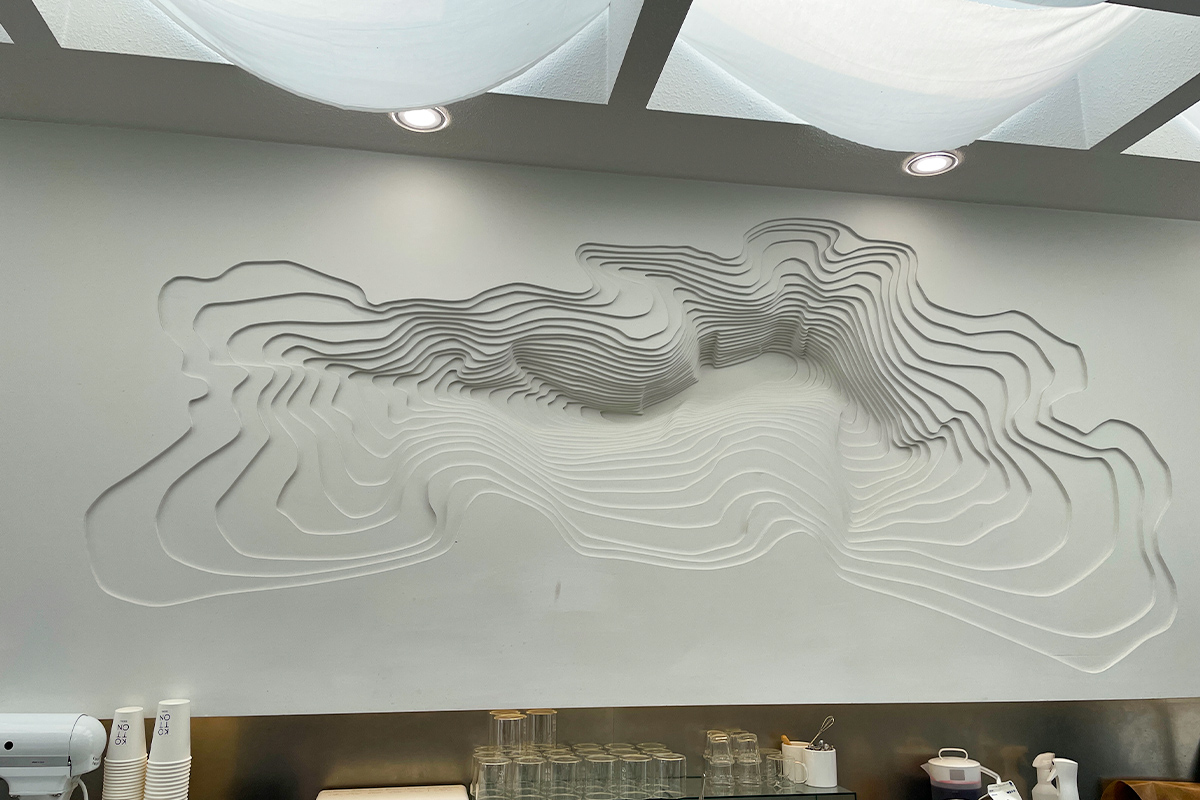 這是一面白色牆壁上的藝術裝飾，位於首爾仁寺洞的 Kotton Seoul 咖啡廳內部，展現咖啡廳的現代設計元素。