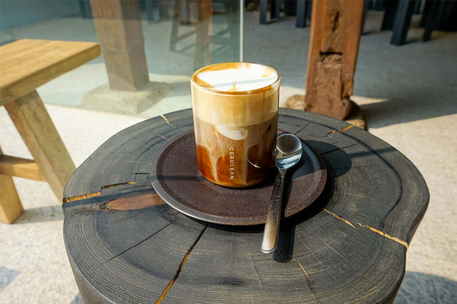 置於粗木桌上的日光下的咖啡，展現 Kotton Seoul 咖啡廳的悠閒氛圍，位於首爾的仁寺洞。