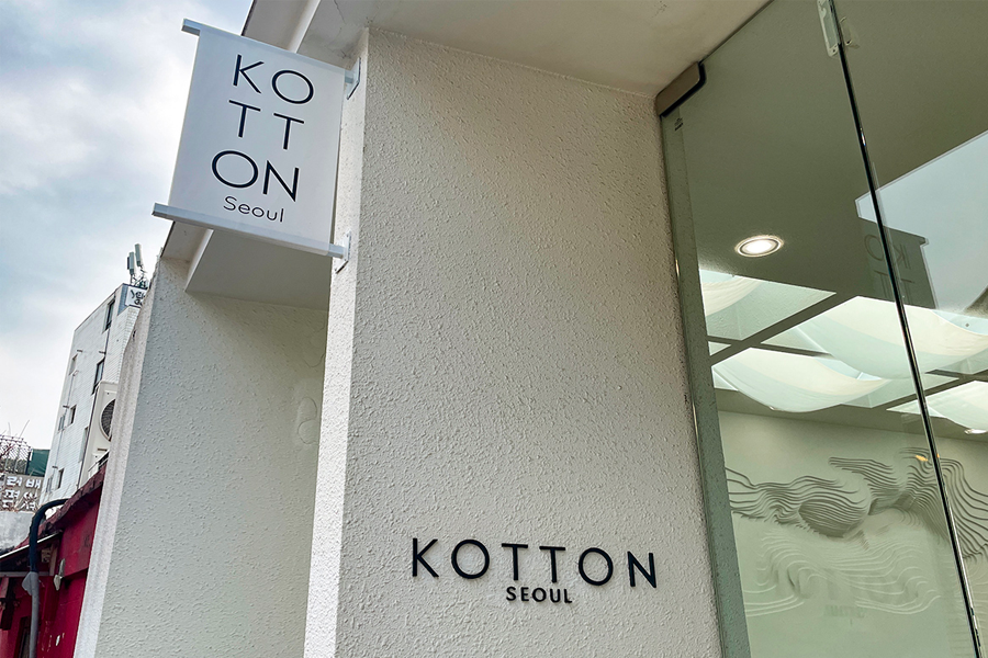 這是 Kotton Seoul 咖啡廳的窗戶和入口，外牆上印有店名，位於首爾仁寺洞的小巷中。