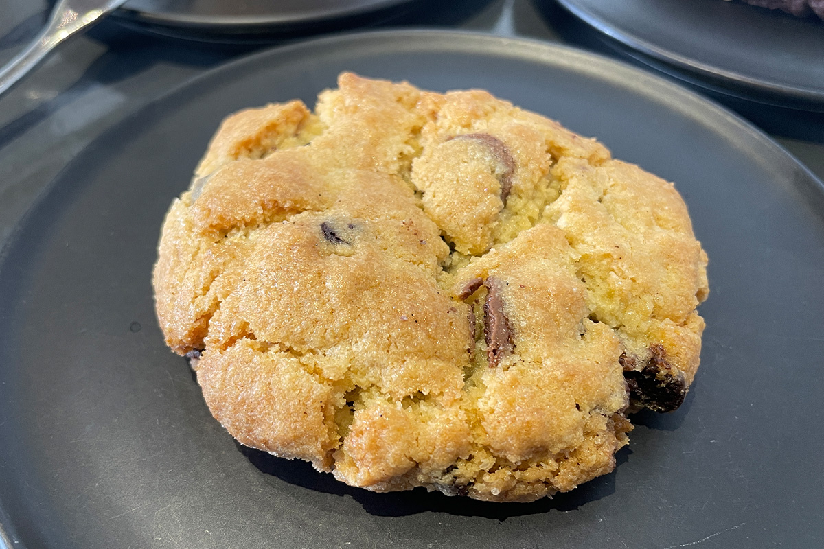 一塊充滿顆粒和巧克力片的手工曲奇餅，來自首爾仁寺洞的 Kotton Seoul 咖啡廳，作為咖啡搭配的完美甜點。