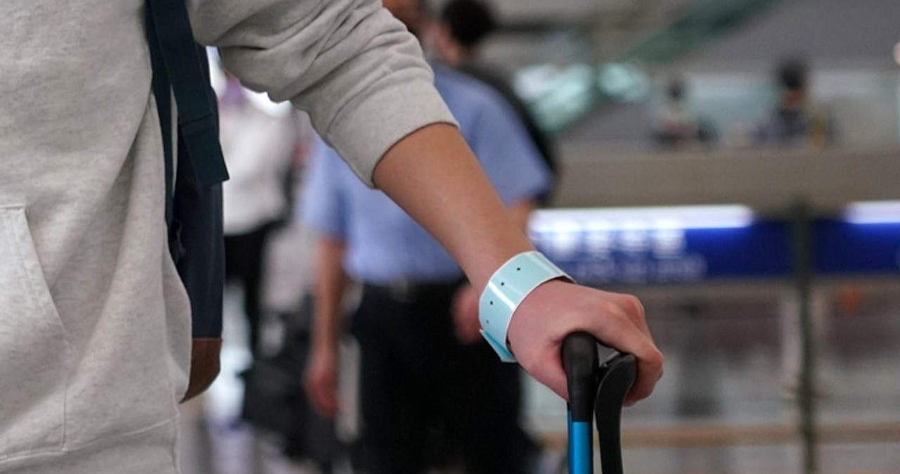 機場隔離政策：旅客穿戴灰色衣服及藍色隔離手環，正在拖行李。來源：CREATRIP