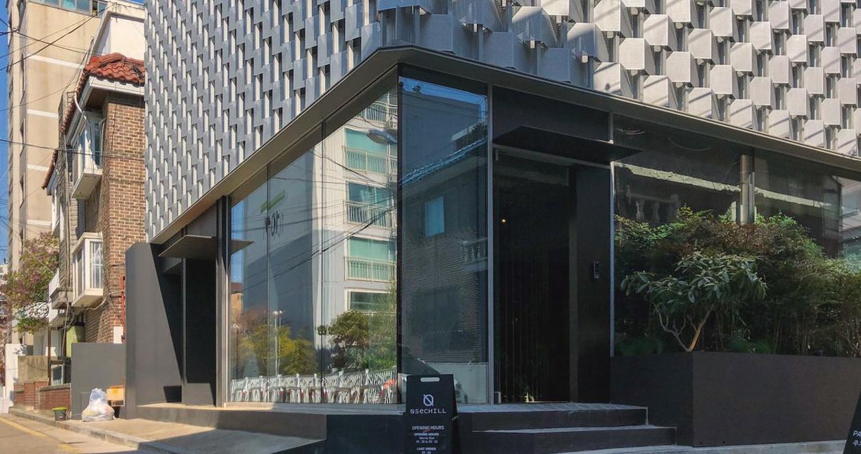 Hình ảnh bên ngoài của quán cafe Osechill của Song Mino tại Seoul, với thiết kế hiện đại và kính sáng.
