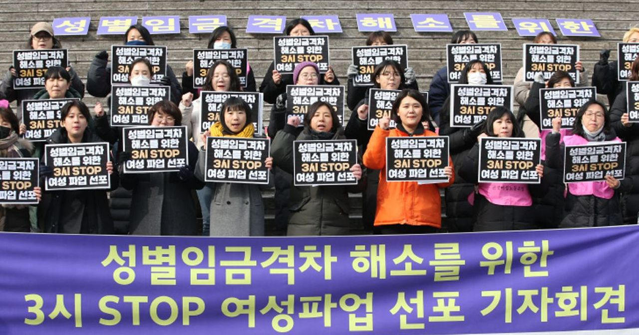 人群舉著反性別歧視的標語牌示威，強調韓國職場性別不平等問題。