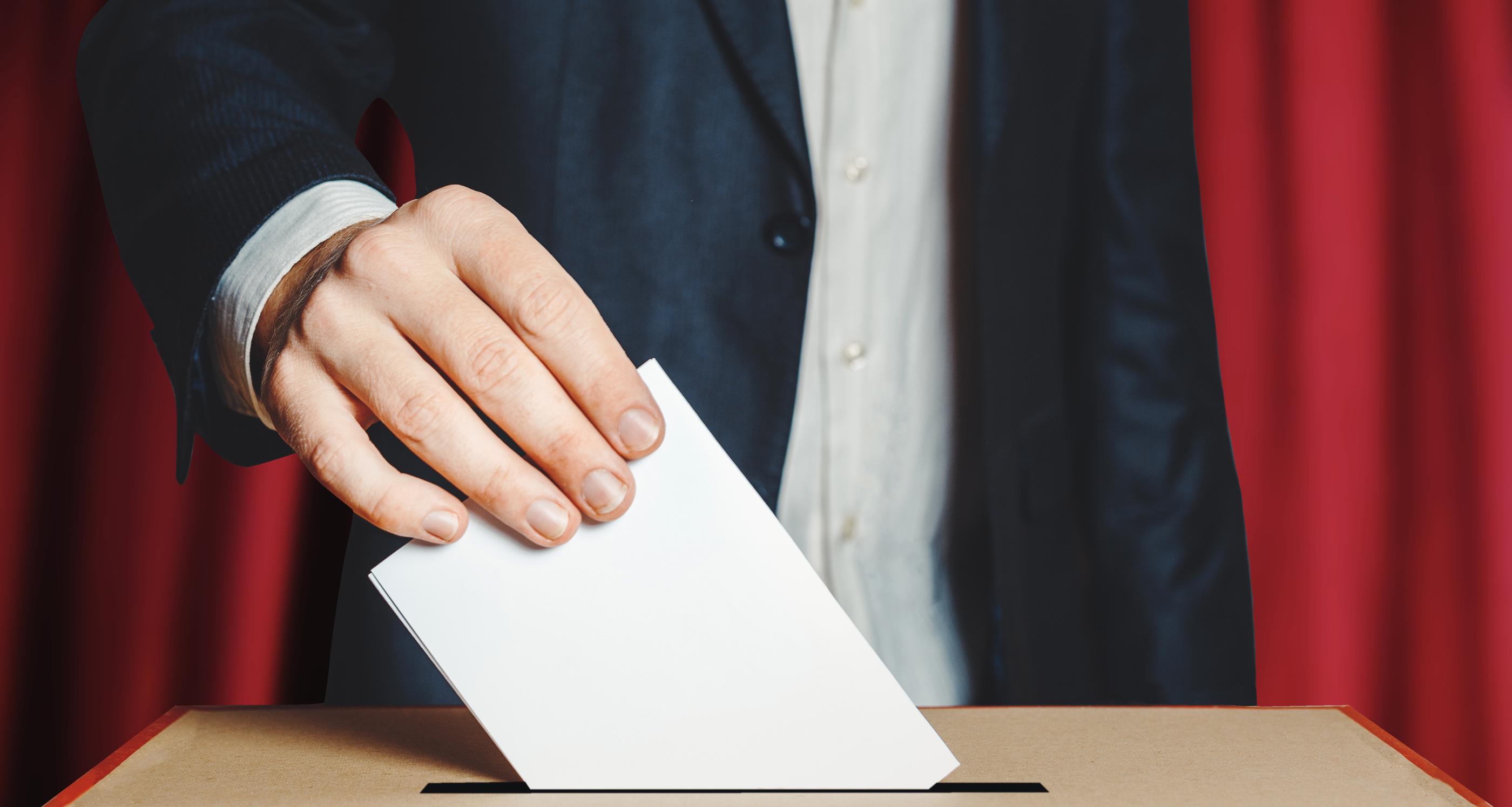 男子在投票箱前投下選票，象徵民主選舉的進行