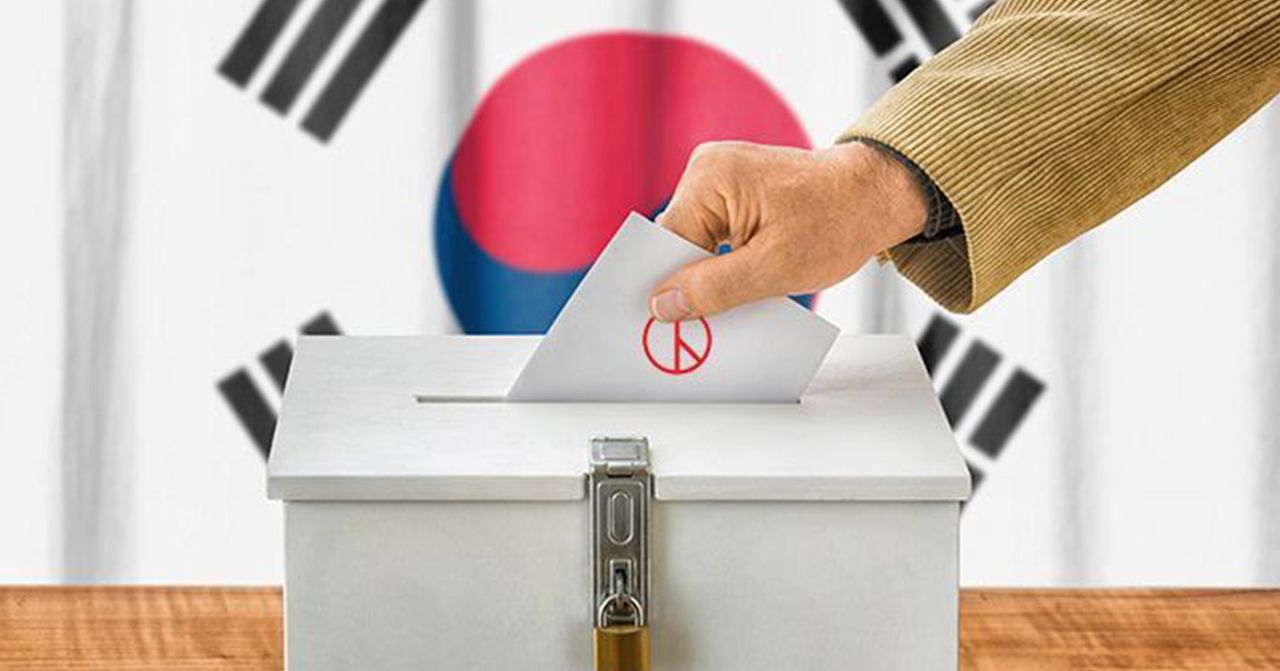 韓國選舉文化，展示選舉中心的投票箱，背景有韓國國旗，象徵民主過程。