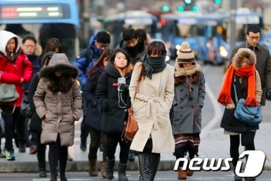 A group of people in Seoul bundled up in winter coats, scarves, and beanies, reflecting common winter fashion in South Korea amid cold temperatures.