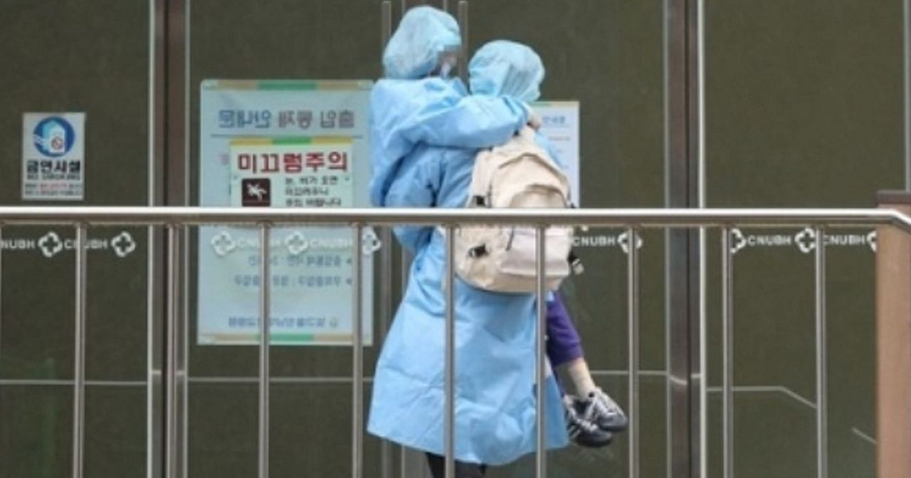 一名穿著防護服的醫護人員與小女孩擁抱，在武漢肺炎科室入口前。