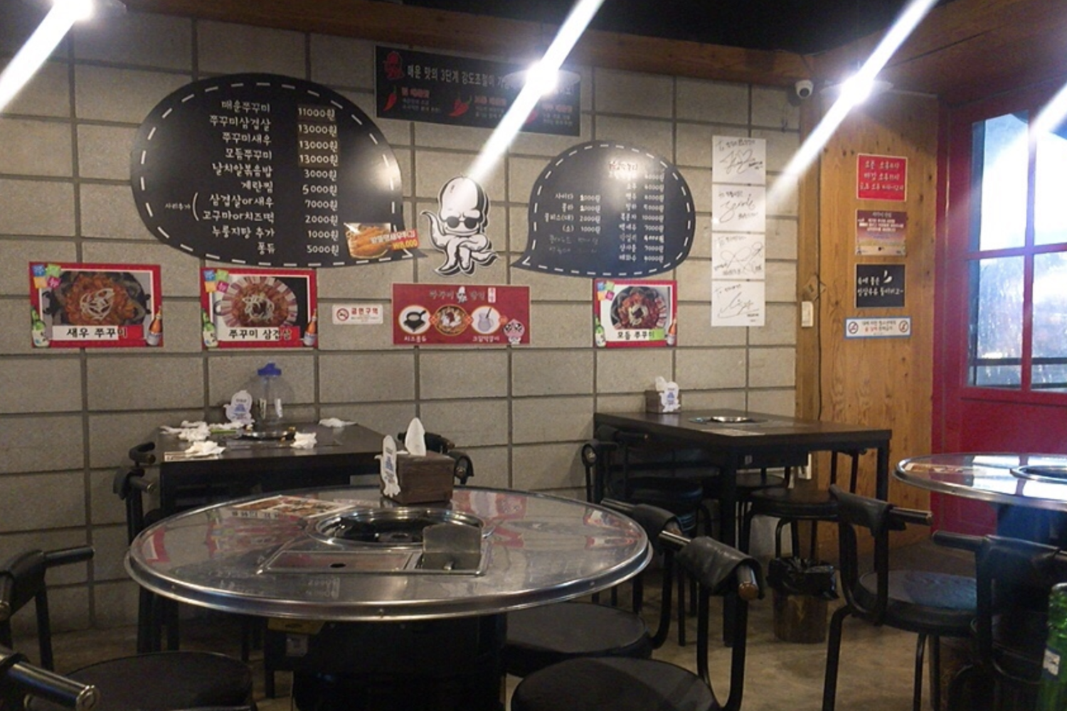 韓國辣炒章魚達人店內熱鬧的用餐景象，簽名牆上有多位名人簽名