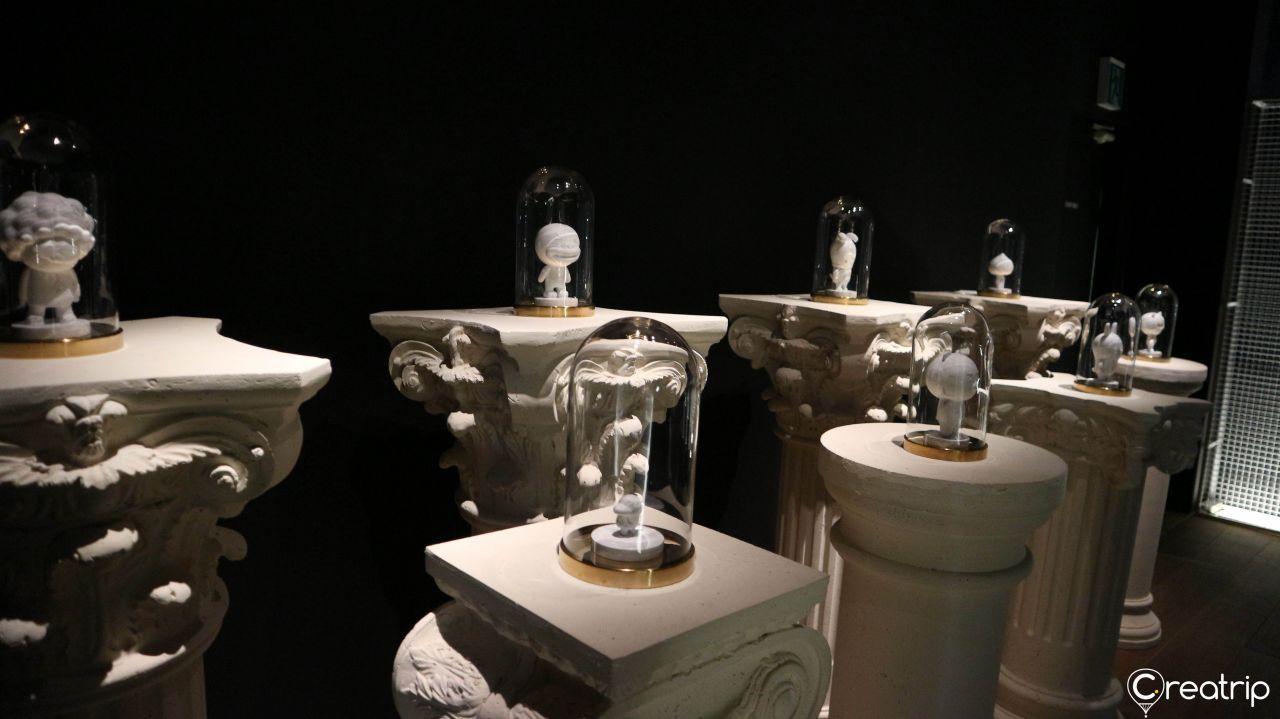 Marble-like statues of Kakao Friends characters placed on elegant pedestals under glass.