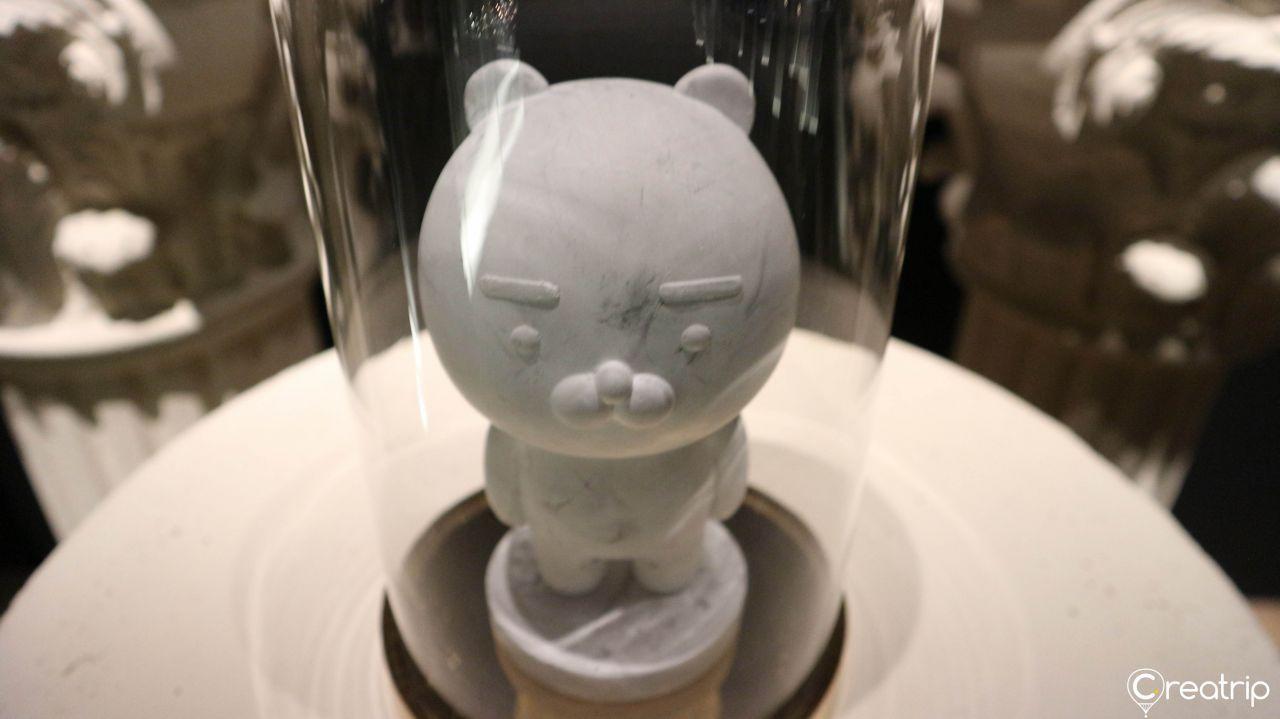 Artistic metallic sculpture pieces with Kakao Friends motifs displayed on a gold base.